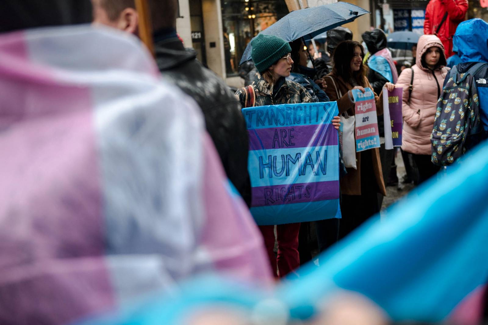 Una persona sosté un cartell que diu "Els drets trans són drets humans" mentre activistes LGBTQ protesten el 17 de març de 2023 davant del consolat dels Estats Units a Mont-real, Canadà, exigint que les persones transgènere i no binàries siguin admeses al Canadà.